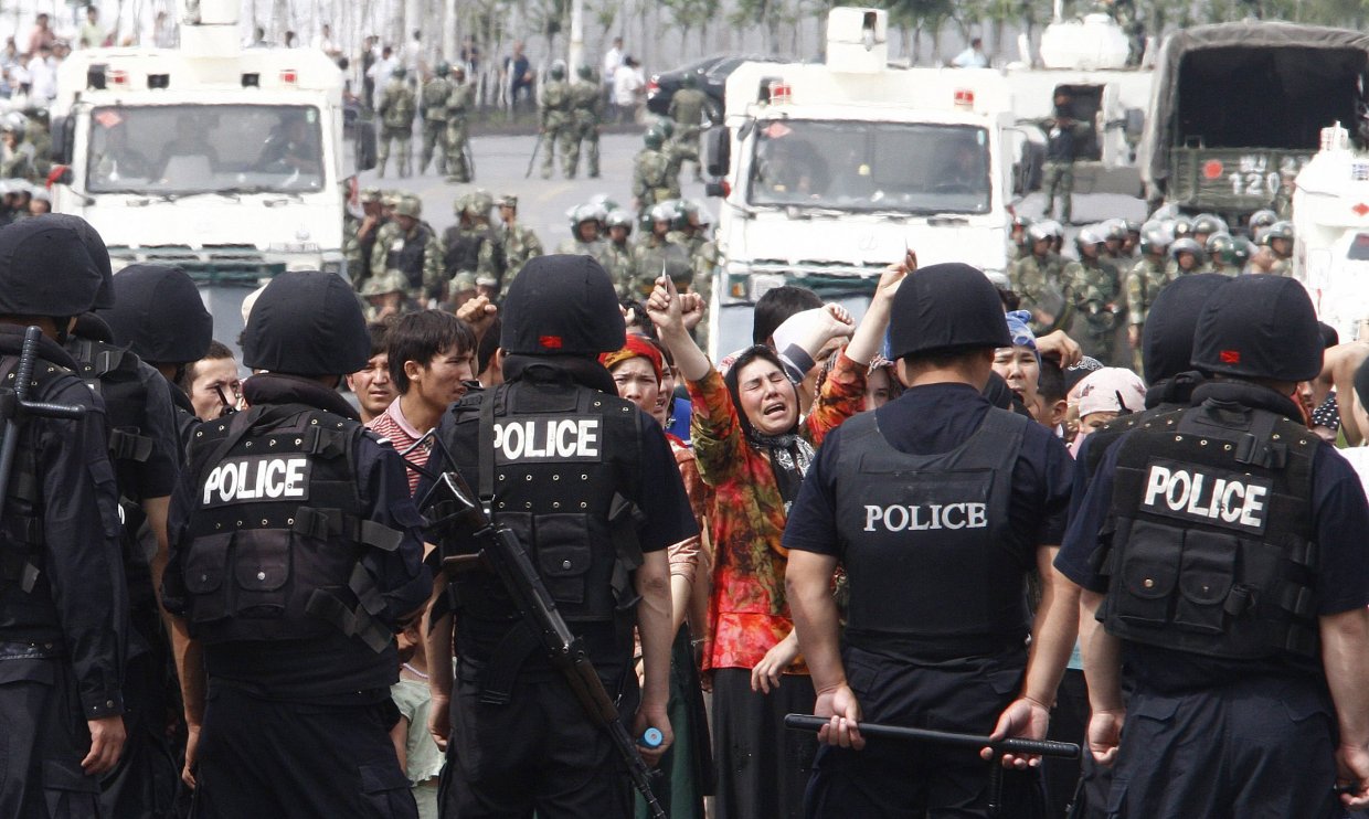 Protestierende Uiguren und chinesische Polizisten in Urumqi, Xinjiang, China.