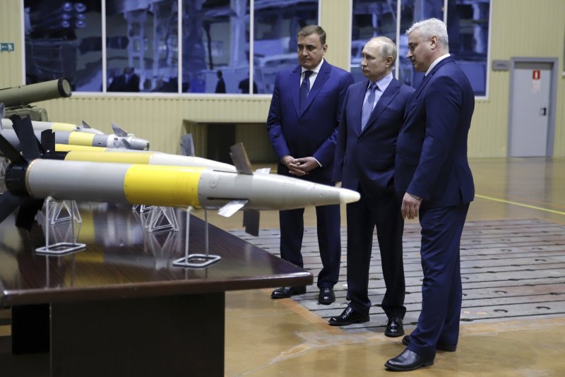 Der russische Präsident Wladimir Putin (M.) besucht eine Waffenfabrik in Tula. Er wird flankiert vom Gouverneur von Tula (l.) und dem Direktor des Rüstungskonzerns Shcheglovsky Val. Die drei Männer betrachten mehrere Raketensprengköpfe, die sich im Bildvordergrund befinden.